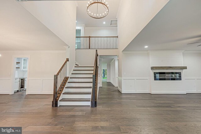 stairway with wood-type flooring, ornamental molding, and beverage cooler