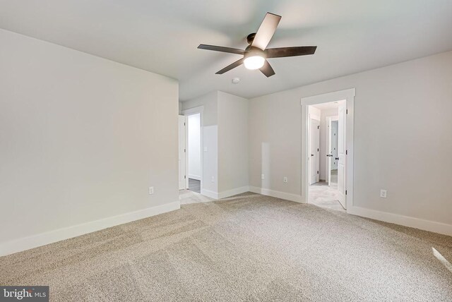 empty room with ceiling fan and light carpet