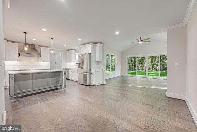 kitchen featuring white cabinetry, light countertops, stainless steel refrigerator with ice dispenser, backsplash, and custom exhaust hood