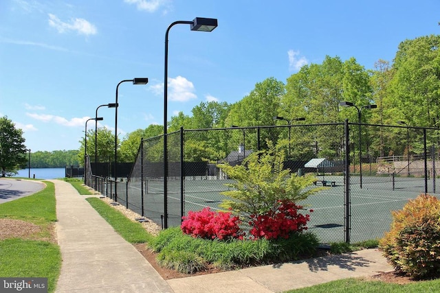 view of tennis court featuring a water view