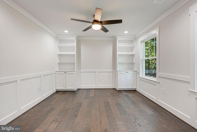 empty room featuring crown molding, dark wood-type flooring, built in features, and ceiling fan