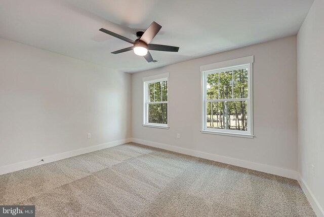 spare room with light colored carpet, ceiling fan, and baseboards