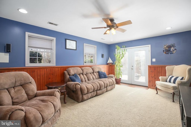 living area featuring visible vents, carpet floors, wainscoting, and french doors