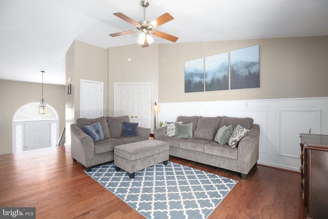 living area with a wainscoted wall, a ceiling fan, wood finished floors, a decorative wall, and lofted ceiling