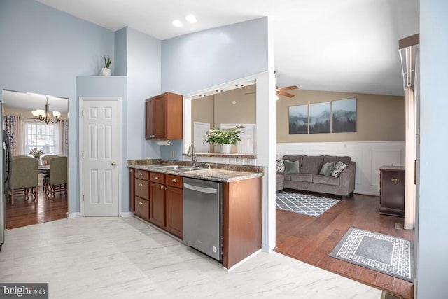 kitchen featuring brown cabinetry, light wood finished floors, a sink, dishwasher, and ceiling fan with notable chandelier