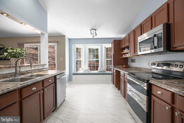 kitchen with a sink, dark countertops, appliances with stainless steel finishes, and a healthy amount of sunlight