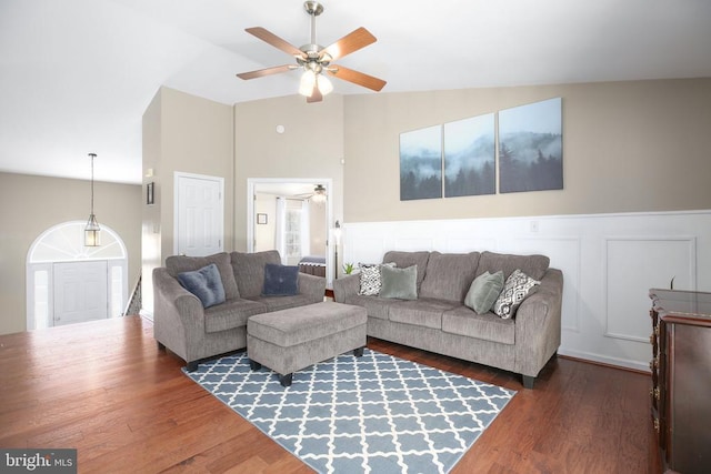 living room featuring a wainscoted wall, vaulted ceiling, wood finished floors, a decorative wall, and a ceiling fan