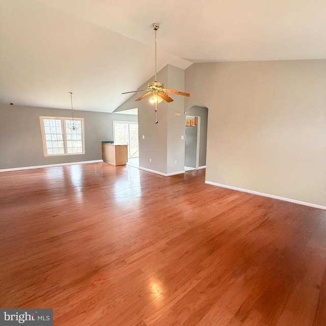 unfurnished living room featuring a ceiling fan, baseboards, high vaulted ceiling, arched walkways, and light wood-type flooring