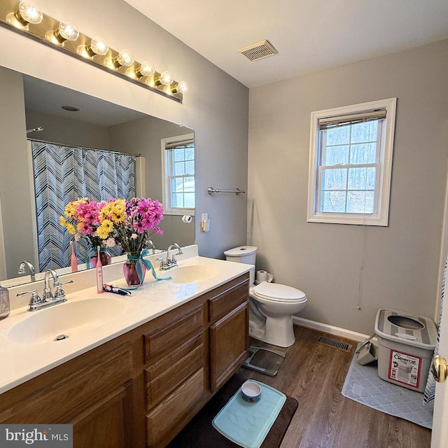 full bath featuring toilet, wood finished floors, visible vents, and a sink