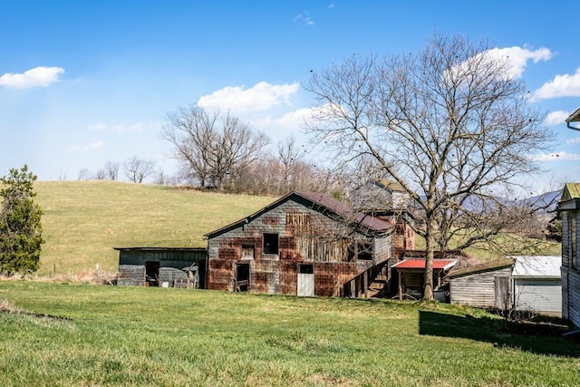 rear view of property featuring an outbuilding, a yard, and a rural view