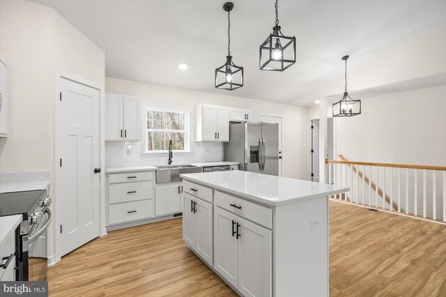 kitchen featuring pendant lighting, sink, white cabinets, a center island, and stainless steel appliances