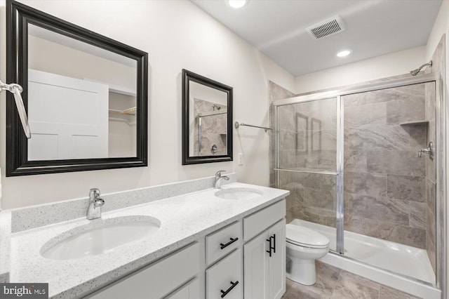 bathroom with a shower with door, vanity, and toilet