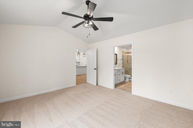 unfurnished bedroom featuring light carpet, vaulted ceiling, and ensuite bathroom