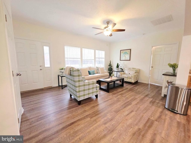 living area featuring ceiling fan, visible vents, baseboards, and wood finished floors