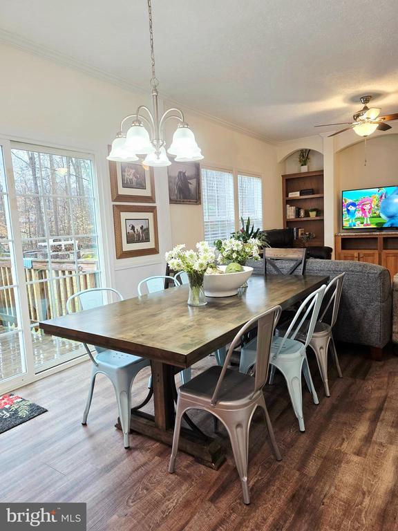 dining room featuring ceiling fan with notable chandelier, crown molding, and wood finished floors