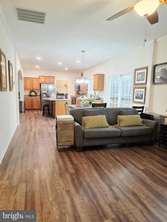 living area with visible vents, baseboards, ornamental molding, wood finished floors, and arched walkways