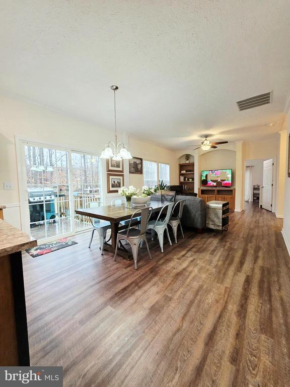 dining area with ceiling fan with notable chandelier, wood finished floors, visible vents, and a textured ceiling