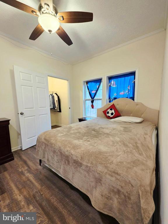 bedroom with baseboards, dark wood-type flooring, ceiling fan, and crown molding