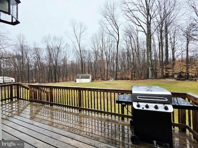 wooden deck with a storage unit, a yard, an outbuilding, and a grill