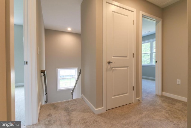 corridor featuring carpet floors, recessed lighting, baseboards, and an upstairs landing