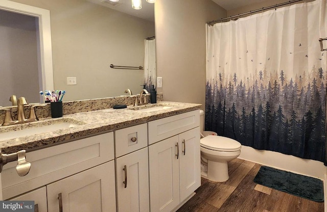 bathroom with a sink, double vanity, toilet, and wood finished floors