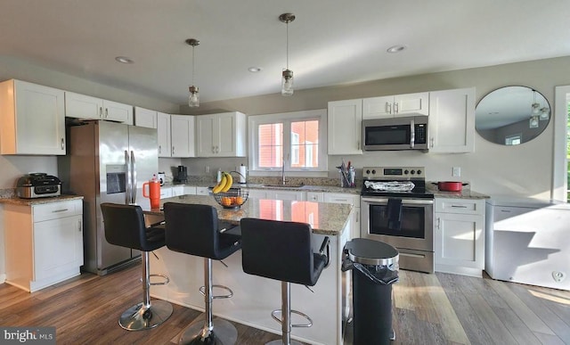 kitchen featuring white cabinets, appliances with stainless steel finishes, a kitchen island, and dark wood finished floors