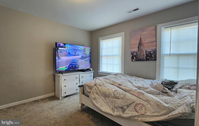 bedroom with baseboards, light colored carpet, and visible vents