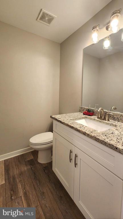 bathroom with visible vents, wood finished floors, vanity, baseboards, and toilet