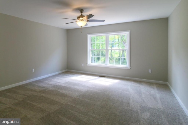 spare room with carpet floors, ceiling fan, visible vents, and baseboards