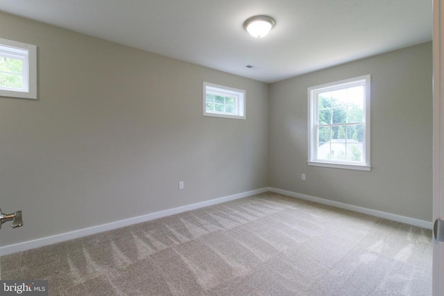 empty room with baseboards, visible vents, and light carpet