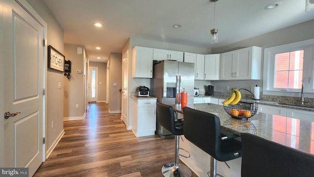 kitchen with a sink, stainless steel refrigerator with ice dispenser, wood finished floors, and white cabinetry