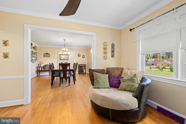 sitting room with ornamental molding, wood-type flooring, and a chandelier