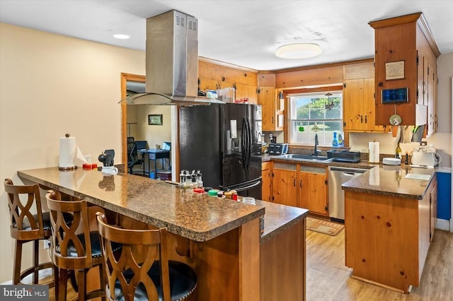 kitchen with sink, black fridge, island range hood, dishwasher, and kitchen peninsula