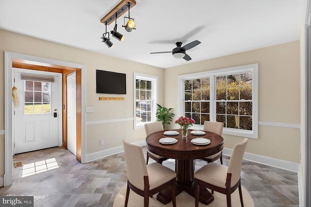 dining space with stone finish floor, a ceiling fan, and baseboards