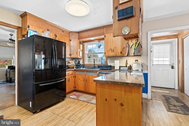 kitchen with sink, ceiling fan, black refrigerator, kitchen peninsula, and light wood-type flooring