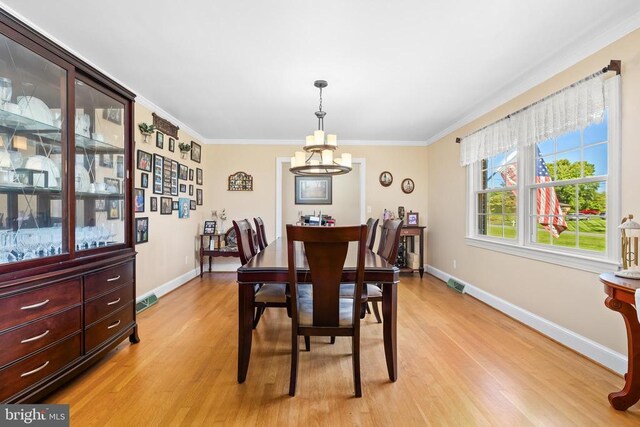 dining space featuring crown molding, a notable chandelier, and light hardwood / wood-style floors