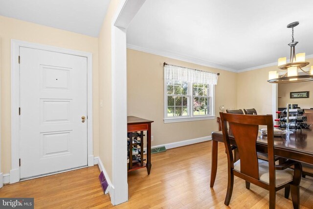 dining room featuring an inviting chandelier, crown molding, and light wood-type flooring