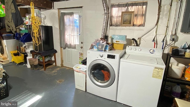 laundry room with concrete block wall, laundry area, and separate washer and dryer