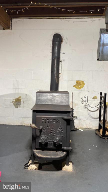 interior details featuring unfinished concrete floors, concrete block wall, and a wood stove