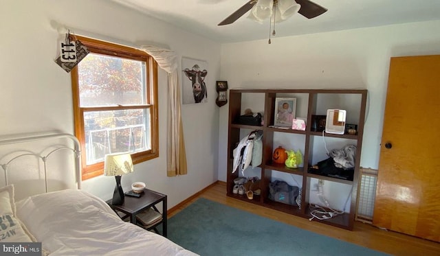 bedroom with a ceiling fan, baseboards, and wood finished floors