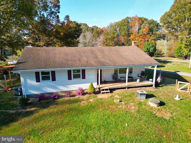 single story home featuring roof with shingles, a wooden deck, fence, a front lawn, and central AC