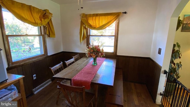 dining room featuring dark hardwood / wood-style flooring and wooden walls