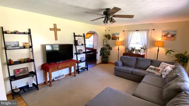 living room featuring arched walkways, a textured ceiling, and a ceiling fan
