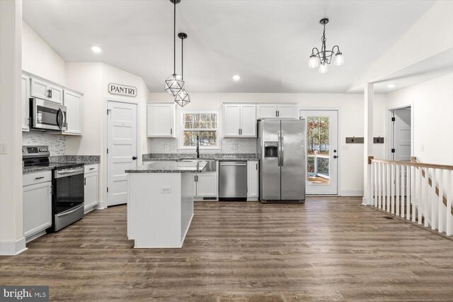 kitchen featuring stainless steel appliances, a kitchen island, white cabinets, and decorative light fixtures