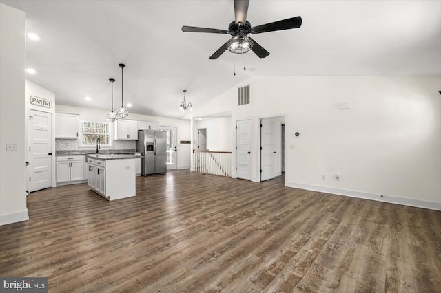 unfurnished living room featuring sink, dark wood-type flooring, ceiling fan with notable chandelier, and high vaulted ceiling