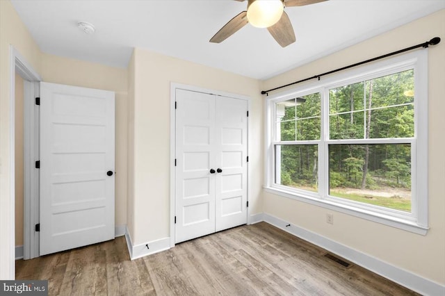 unfurnished bedroom with light hardwood / wood-style flooring, a closet, and ceiling fan