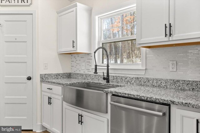 kitchen featuring sink, stainless steel dishwasher, white cabinets, and light stone counters