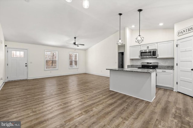 kitchen featuring white cabinetry, hanging light fixtures, dark stone counters, stainless steel appliances, and hardwood / wood-style floors