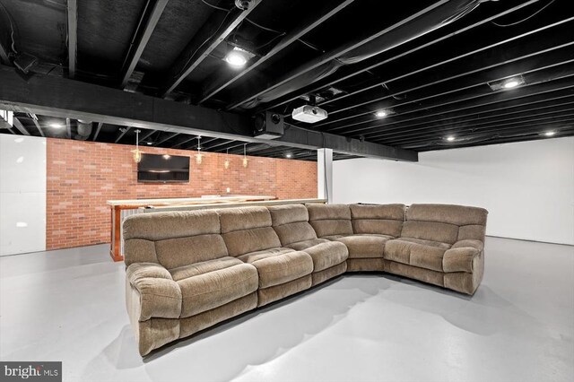 living room featuring brick wall and concrete floors