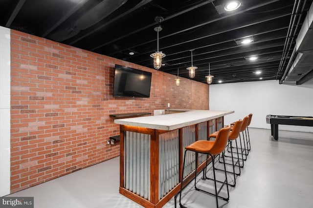 bar featuring hanging light fixtures and brick wall